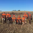 Photo of a group of hunters with their birds in a field.